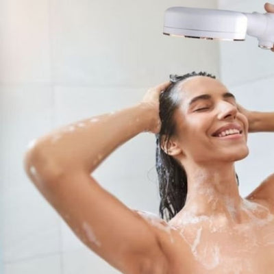 Pommeau douche avec jet puissant sur tete femme sourit ecosensation